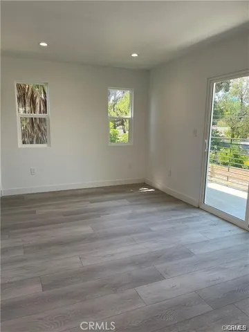 a view of an empty room with window and wooden floor