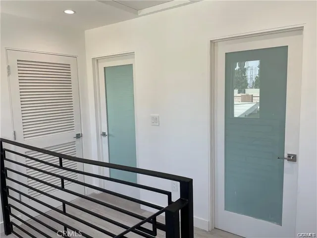 a view of a hallway with wooden floor and a bathroom