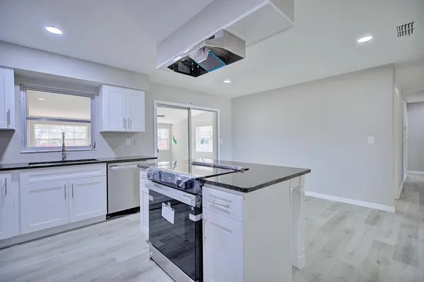 a kitchen with granite countertop a sink stainless steel appliances and white cabinets