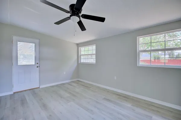 a view of empty room with wooden floor and fan