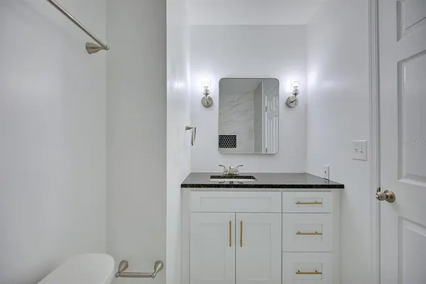 a bathroom with a granite countertop sink and a mirror with toilet