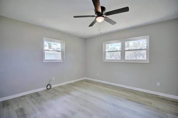 a view of empty room with wooden floor and fan