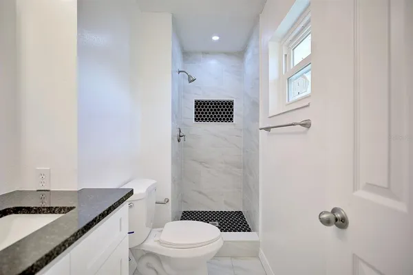 a bathroom with a granite countertop sink toilet and shower