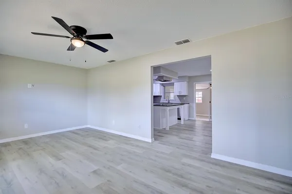 a view of a kitchen with wooden floor a ceiling fan and windows