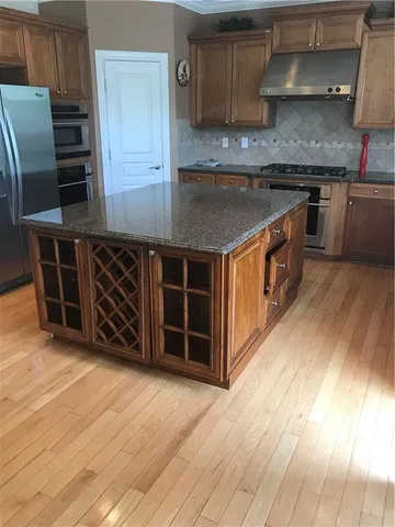 a kitchen with stainless steel appliances granite countertop a stove a sink and a refrigerator