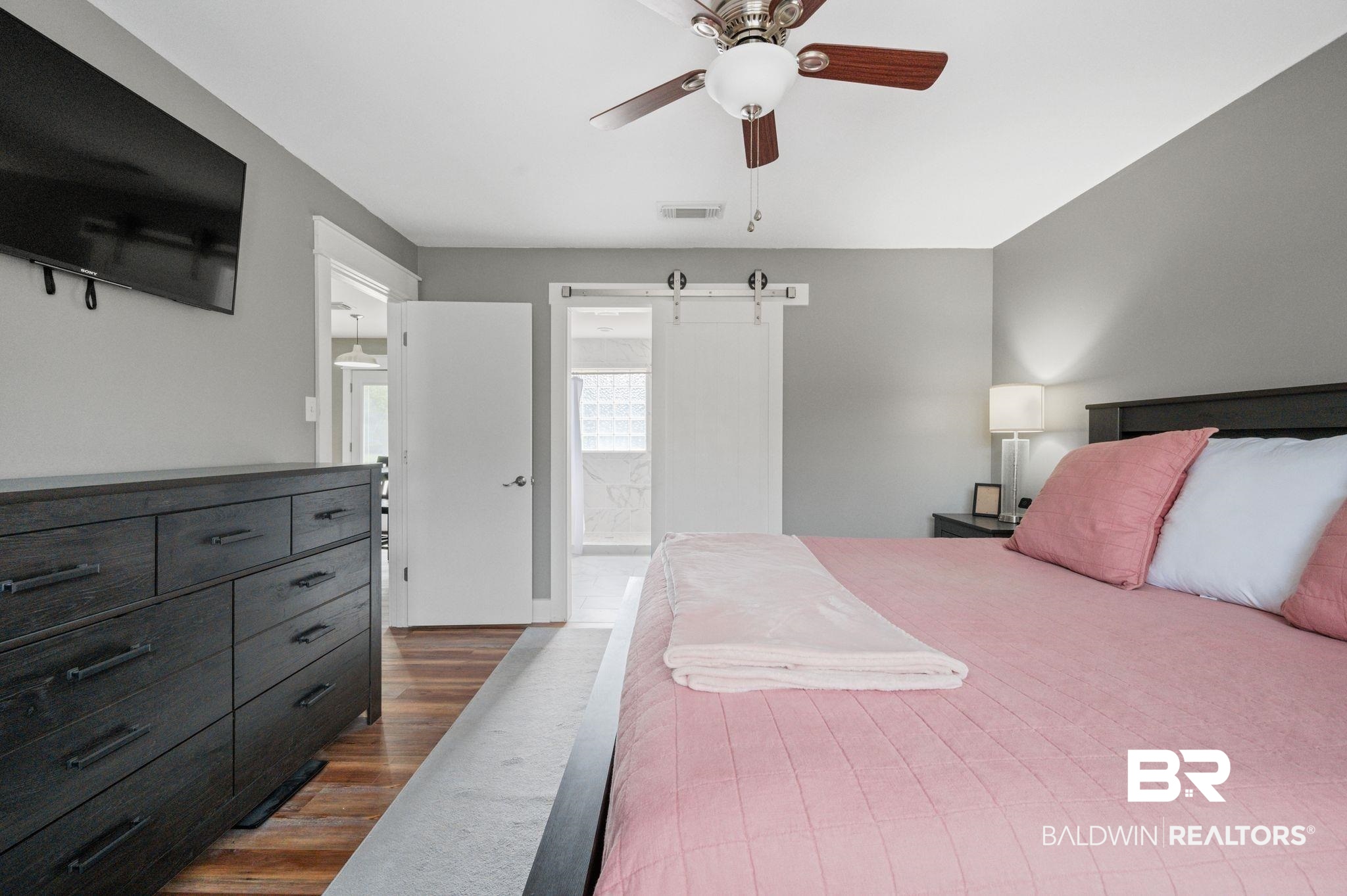 1107 North Oak Street Loxley, AL 36551 - Photo 13 of 40 Bedroom featuring a barn door, ceiling fan, ensuite bathroom, and dark hardwood / wood-style flooring