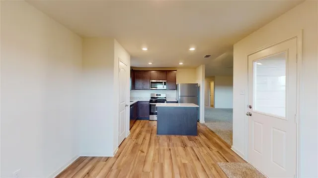 a large kitchen with a wooden floor and stainless steel appliances