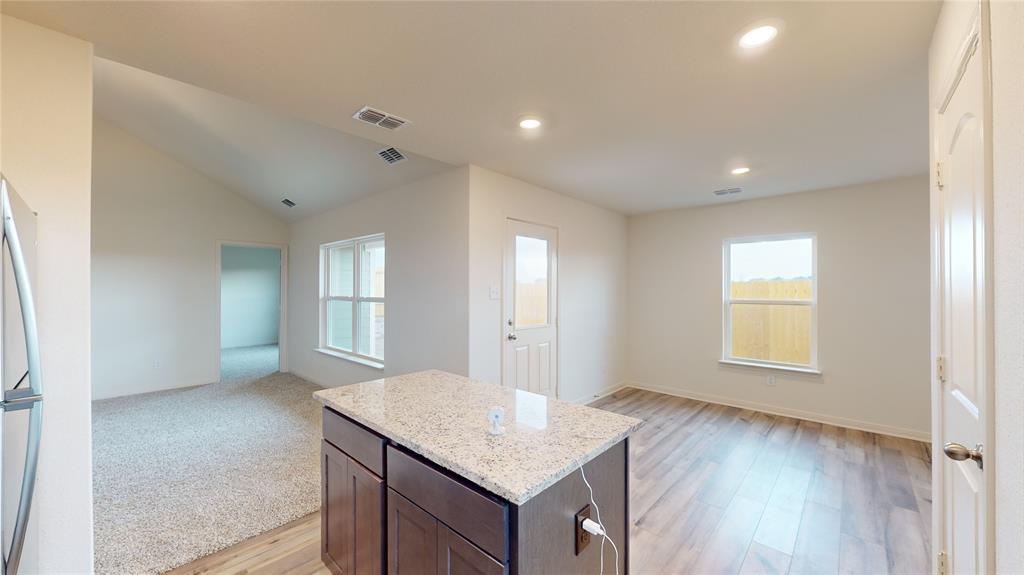 8012 White Sulphur Road Ponder, TX 76259 - Photo 39 of 39 Kitchen featuring open floor plan, light stone countertops, dark brown cabinets, a center island, and light wood-style floors