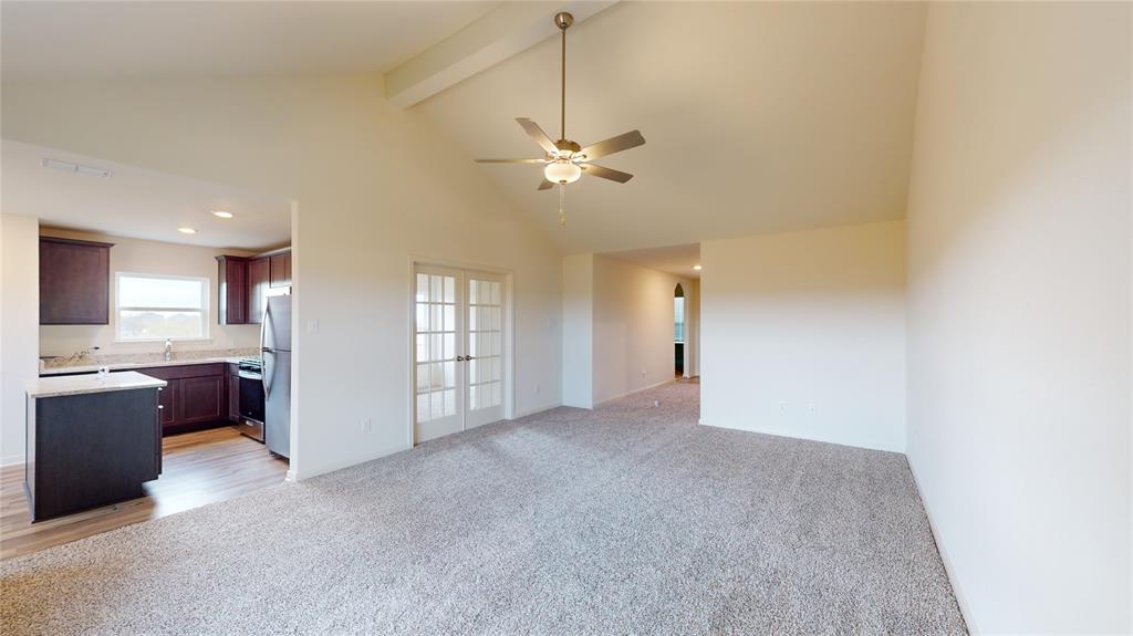 8012 White Sulphur Road Ponder, TX 76259 - Photo 27 of 39 Unfurnished living room featuring high vaulted ceiling, light colored carpet, ceiling fan, beam ceiling, and french doors