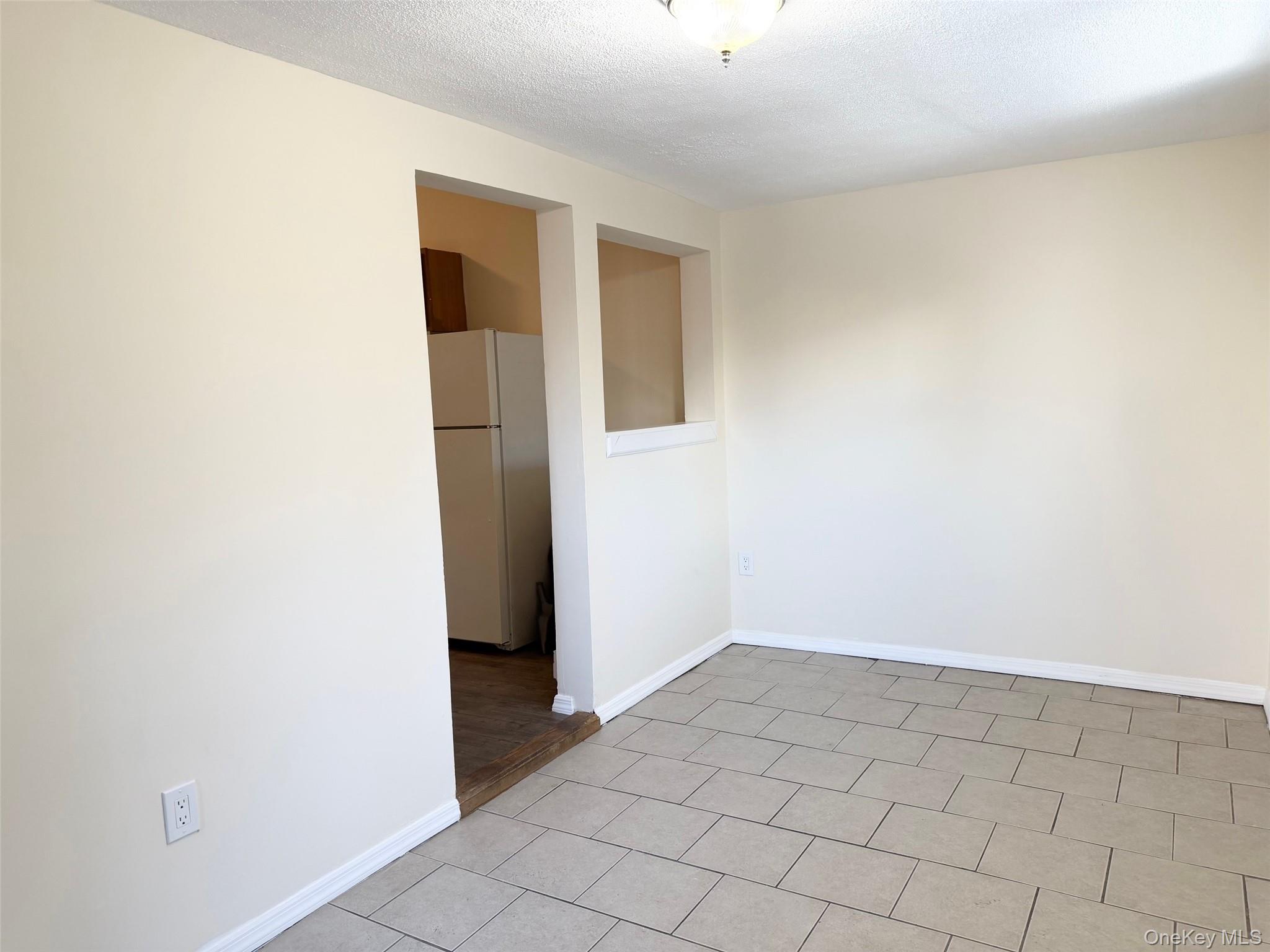 188 Hallock Landing Road Rocky Point, NY 11778 - Photo 8 of 25 Spare room featuring a textured ceiling and light tile patterned flooring