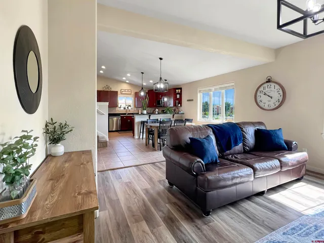 a living room with furniture a chandelier and wooden floor