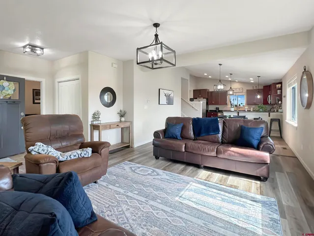 a living room with furniture a chandelier and a wooden floor