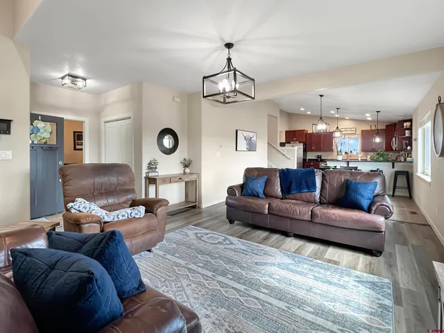 a living room with furniture large window and wooden floor