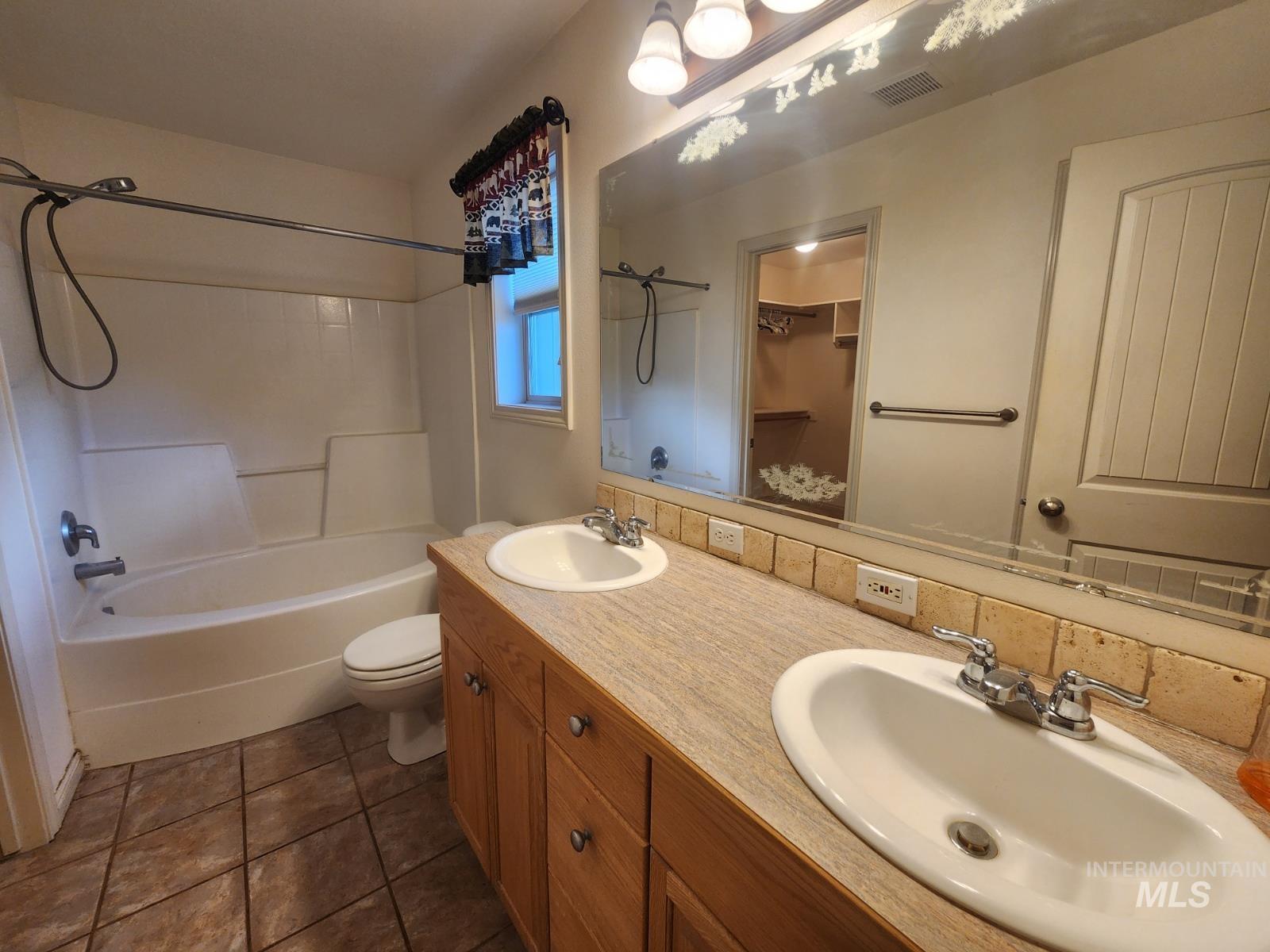 1000 North Rodeo Street Parma, ID 83660 - Photo 13 of 33 Bathroom featuring double vanity, shower / tub combination, a walk in closet, and dark tile patterned floors