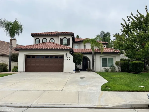 a front view of a house with yard and parking
