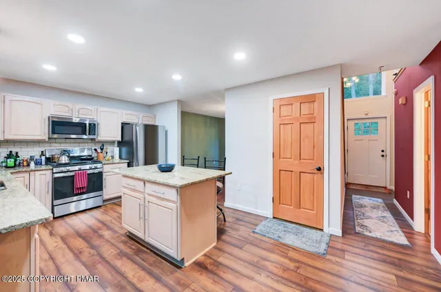 a kitchen with stainless steel appliances granite countertop a sink dishwasher a stove and a refrigerator with wooden floor