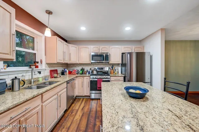 a kitchen with stainless steel appliances granite countertop a stove a sink dishwasher and a microwave oven with wooden cabinets