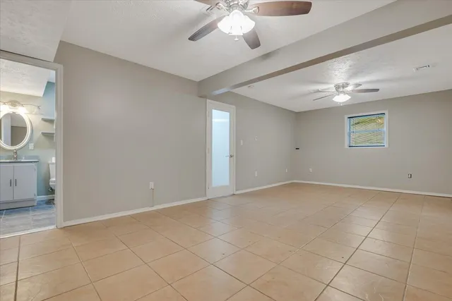 an empty room with windows and chandelier fan