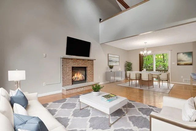 a living room with furniture a rug a fireplace and a large window