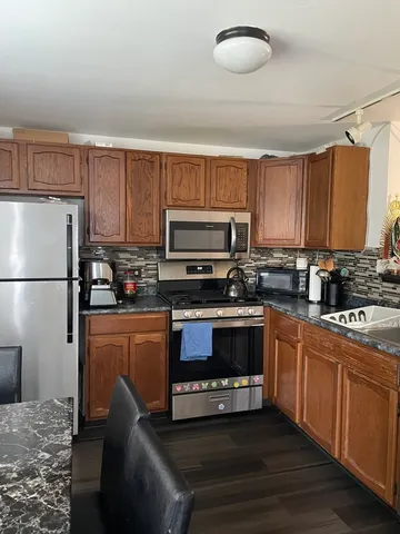 a kitchen with stainless steel appliances granite countertop a refrigerator stove microwave and sink
