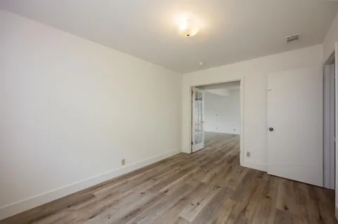 a view of an empty room with wooden floor and closet