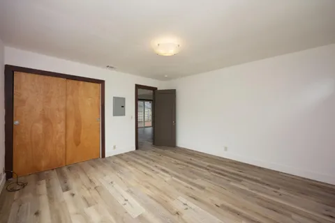 a view of an empty room with wooden floor and a window
