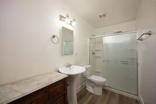 a bathroom with a granite countertop sink toilet a mirror and shower