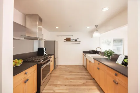 a large kitchen with stainless steel appliances granite countertop a lot of counter space and wooden floor