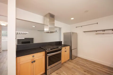 a kitchen with granite countertop a refrigerator and a stove top oven