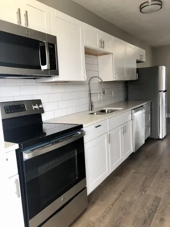 a kitchen with stainless steel appliances granite countertop white cabinets and black stove top oven