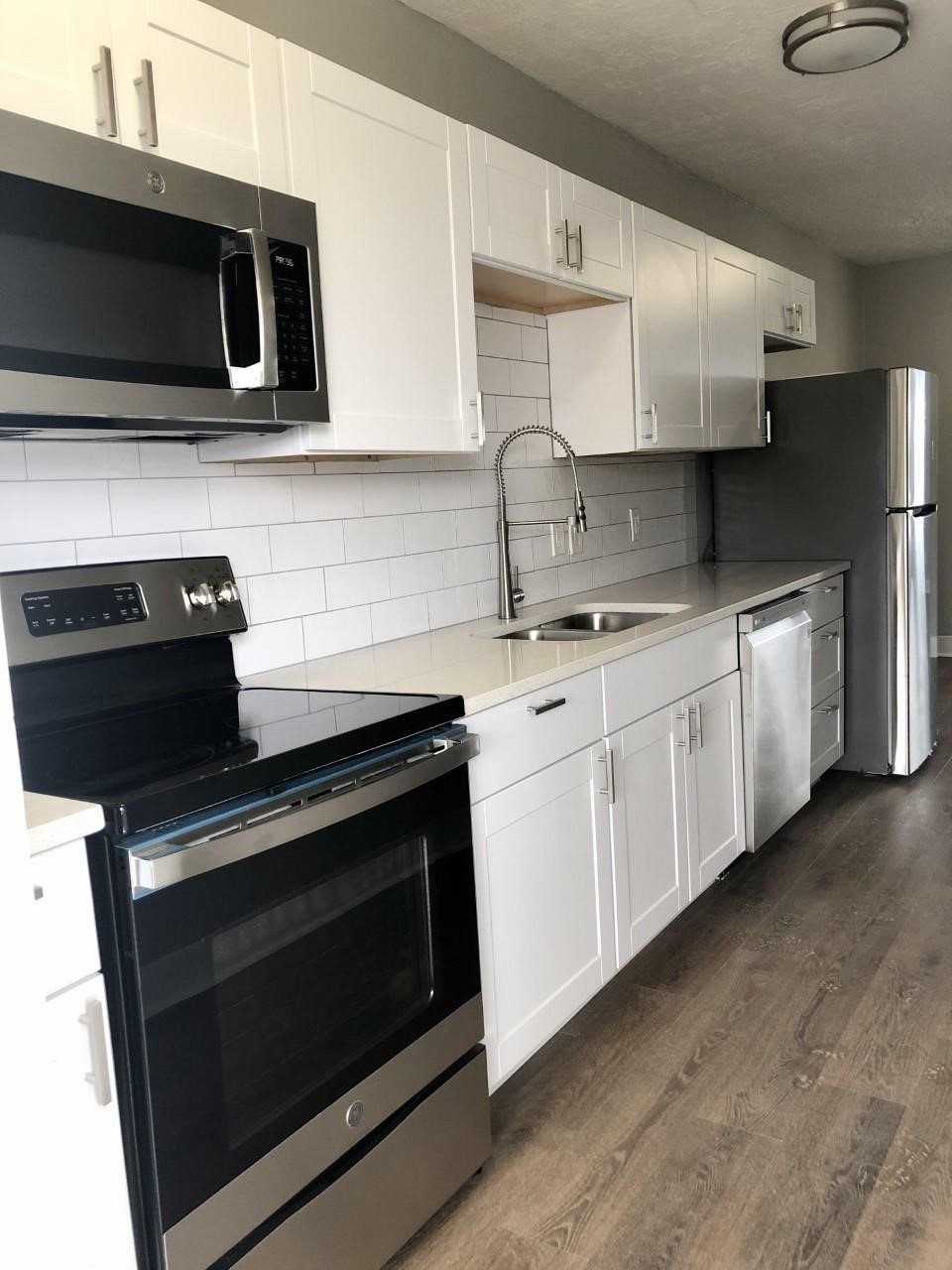 a kitchen with stainless steel appliances granite countertop white cabinets and black stove top oven
