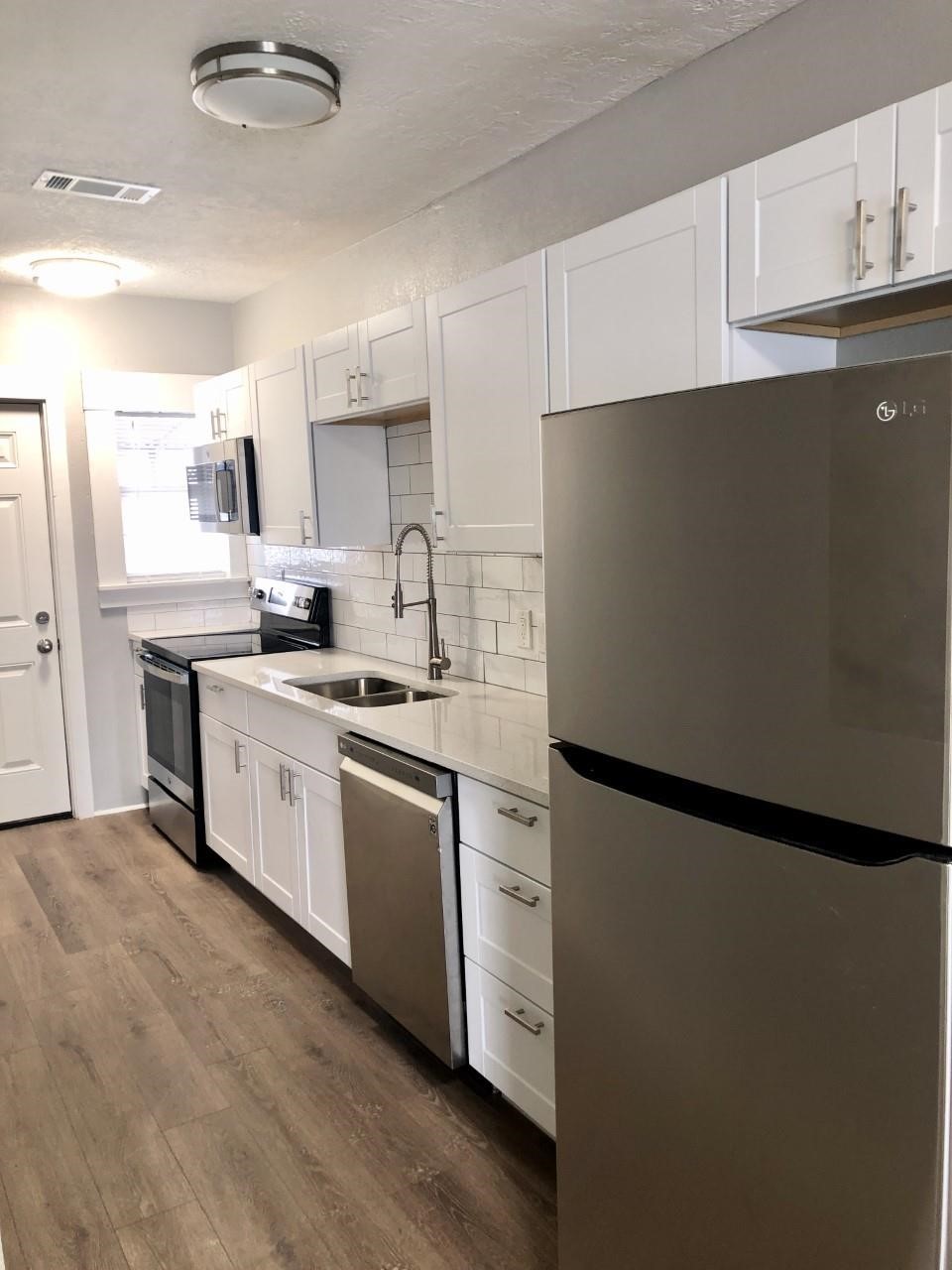 220 Milby Street Houston, TX 77003 - Photo 2 of 11 a kitchen with a sink a refrigerator and cabinets