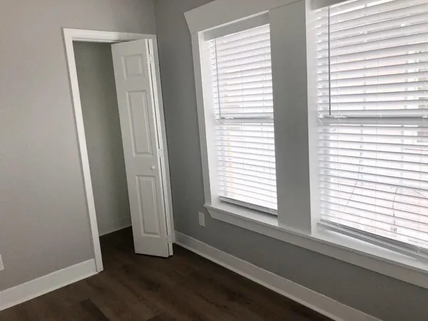 a view of an empty room with wooden floor and a window