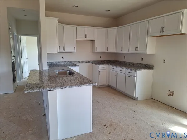 a kitchen with granite countertop white cabinets and a sink