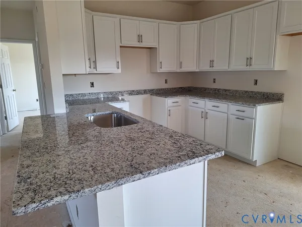 a kitchen with granite countertop a sink and white cabinets