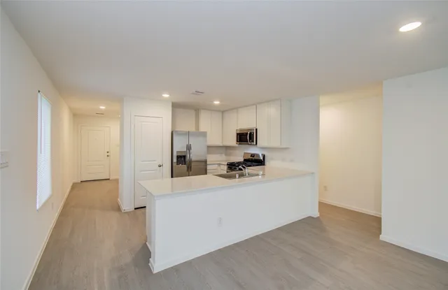 a large white kitchen with white cabinets and stainless steel appliances