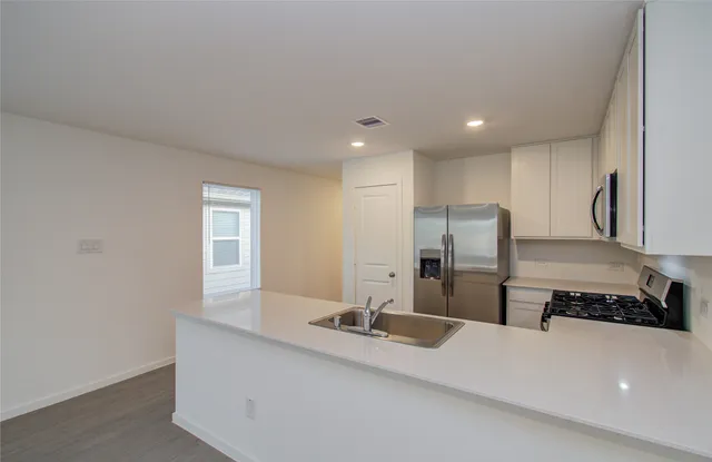 a large white kitchen with a sink and a refrigerator