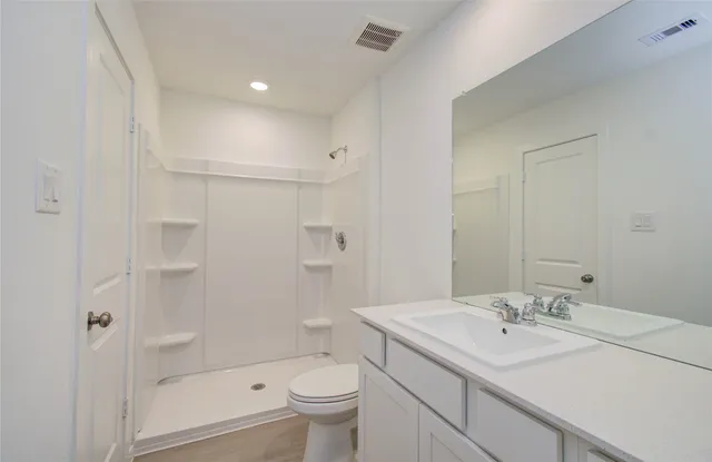a bathroom with a sink toilet double vanity and shower