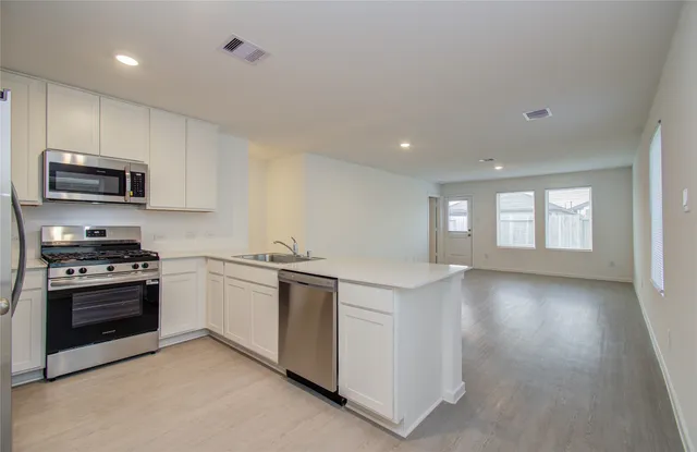 a kitchen with stainless steel appliances granite countertop a stove a sink and a microwave