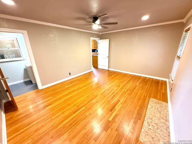 a view of empty room with wooden floor and fan