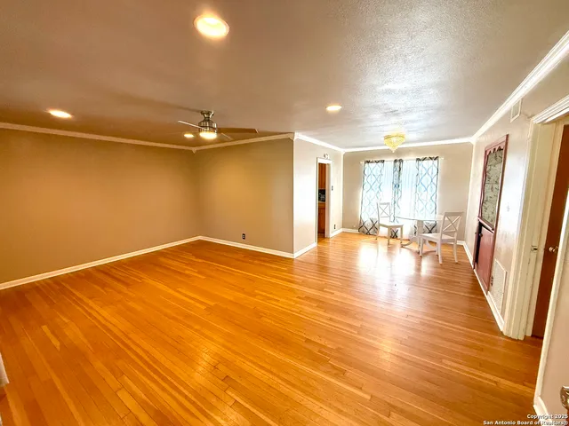 a view of empty room with wooden floor and fan