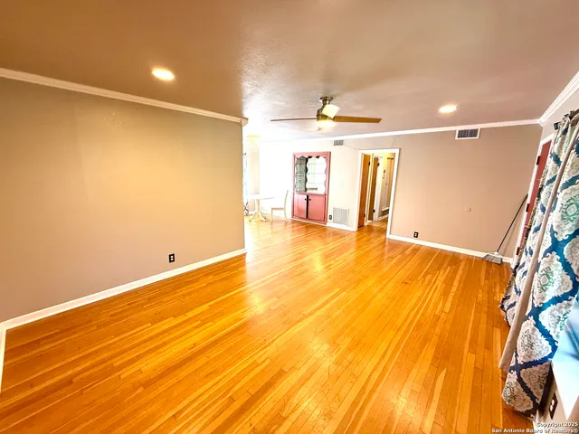 a view of an empty room with window and wooden floor