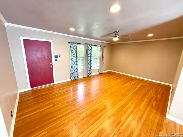 a view of empty room with wooden floor and fan