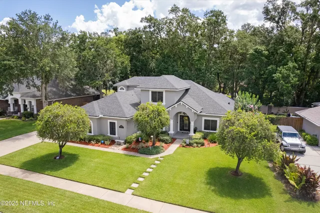 a front view of house and yard with swimming pool and large trees