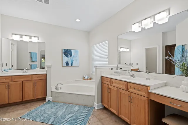 a bathroom with a tub a sink double vanity granite and a bathtub