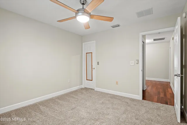 an empty room with closet and a ceiling fan