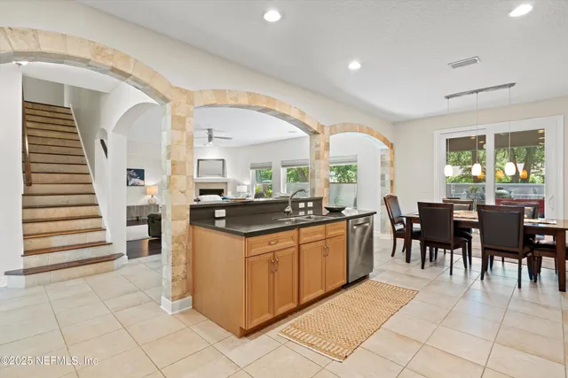 a kitchen with stainless steel appliances granite countertop dining table chairs and a large window