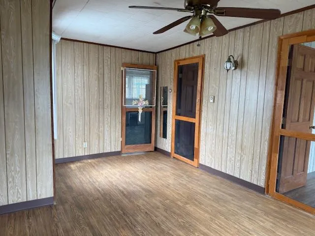 an empty room with wooden floor entryway and windows