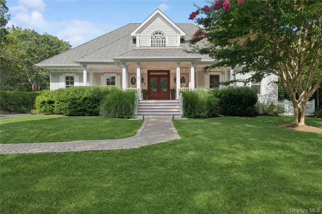 a view of a white house next to a yard with big trees