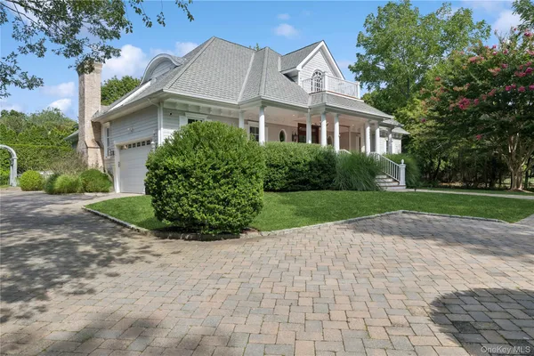 a view of a white house next to a yard with big trees